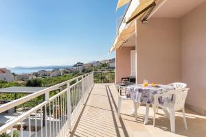 a balcony with a table and chairs and the ocean at Holiday home with several apartments, a pool, sea views and a barbecue near Split in Podstrana