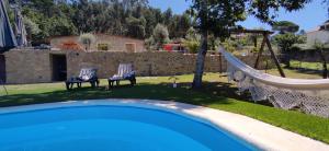 a pool with two chairs and a hammock in a yard at Casas de Correndelos in Ponte de Lima