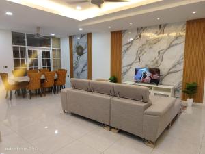 a living room with two couches and a tv on a wall at HOMESTAY IMPIAN AYER MOLEK MUSLYM only in Malacca
