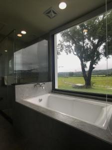 a bath tub in front of a window with a tree at 稻花香民宿 in Chishang