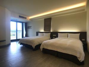a hotel room with two beds and a large window at 稻花香民宿 in Chishang