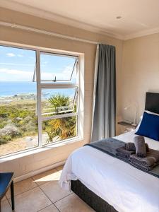 a bedroom with a bed and a large window at On The Hill in Stompneusbaai