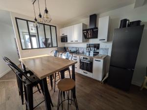 a kitchen with white cabinets and a wooden table and chairs at ANGEL Cozy duplex 2 chambres in Vitré