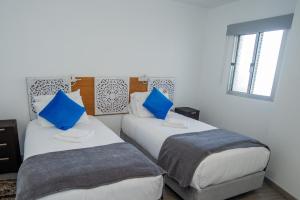 two beds in a room with blue pillows at Sunset Star II With Sea View in Calheta
