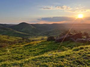 a sunset over a green field with the hills in the background at Casa da Vinagra in Pé da Serra