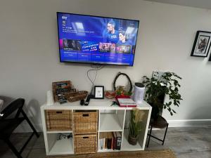 a tv hanging on a wall with a white table at Brain Properties Limited - Garden flat with Parking near QA Hospital in Portsmouth