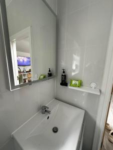 a white bathroom with a sink and a mirror at Brain Properties Limited - Garden flat with Parking near QA Hospital in Portsmouth