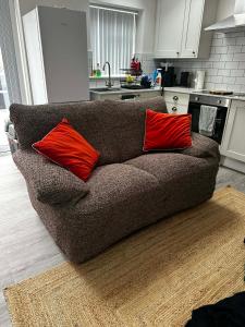 a couch with two red pillows on it in a kitchen at Brain Properties Limited - Garden flat with Parking near QA Hospital in Portsmouth +19 photos