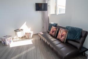 a living room with a leather couch with pillows at Sunset Star II With Sea View in Calheta