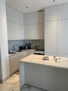 a kitchen with white cabinets and a marble counter top at Trilogy Limassol East Tower Seafront Apartment in Limassol