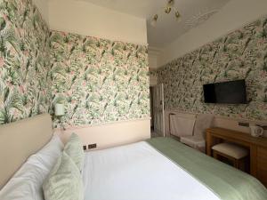 a bedroom with a bed and a tv on the wall at Sonas Guesthouse in Edinburgh