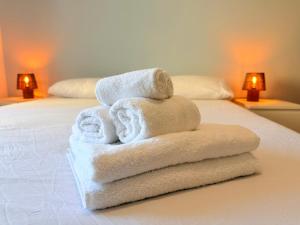 a pile of towels sitting on top of a bed at Meduse Seafront - Attico al Mare in Torvaianica