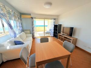 a living room with a white couch and a table at Meduse Seafront - Attico al Mare in Torvaianica +8 photos