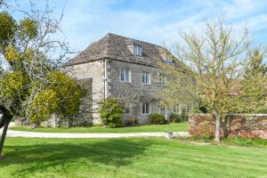 a large stone house with a grass yard at Hares Barn in Trowbridge