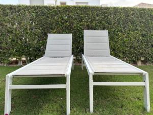two white chairs sitting next to each other on the grass at Spacious Villa - DN32LT in Torre-Pacheco