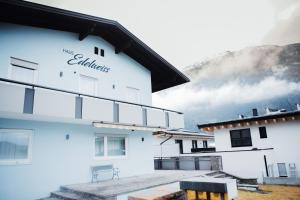 a white building with a mountain in the background at Haus Edelweiss in Tarrenz