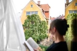 una donna che legge un libro davanti a una casa di Hotel Vis à vis a Lindau