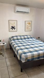 a bedroom with a bed with a blue and white plaid blanket at Las cabañas in Jacó