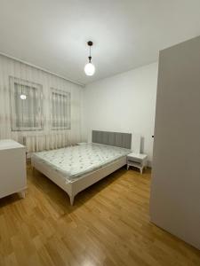 a white bedroom with a bed and a window at Rental House in Mitrovica