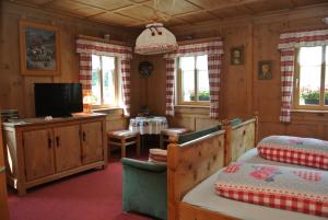 a bedroom with a bed and a tv and windows at Pension Hof zur Stilli in Davos