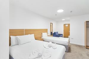 two beds in a hotel room with white sheets at Park Hotel in Ilford