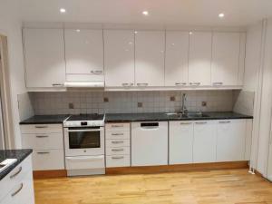 a white kitchen with white cabinets and a wooden floor at Workers Stay - Temporary House Gothenburg in Gothenburg