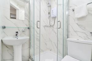 a white bathroom with a shower and a sink at Park Hotel in Ilford +38 photos