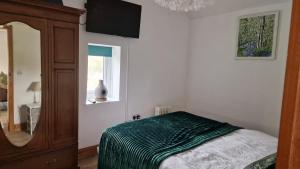 a bedroom with a bed and a dresser and a mirror at Rose Cottage Solway Self Catering in Cardurnock