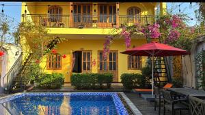 a yellow house with a pool and a red umbrella at Hoàng Doji de Villa in Thôn Dương Xuân Hạ
