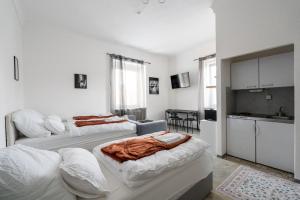a white room with two beds and a kitchen at COY Apartments Leoben - Central near Uni & Station with 24 7 Check-in in Leoben