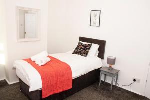 a bedroom with a bed with a red blanket at 3 Bed - Shefa Homes in Manchester