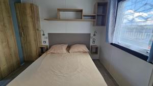 a small bed in a room with a window at Mobilhome Normandie in Litteau