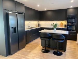 a kitchen with black cabinets and a island with bar stools at Workers Stay - Temporary House Stockholm in Rönninge