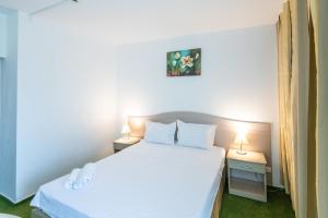 a bedroom with a white bed and two night stands at Complex Bran Brad Bega in Eforie Nord