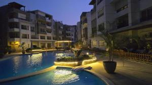 a large swimming pool with lights in front of buildings at Maison 7 Mirage Resort in Cairo