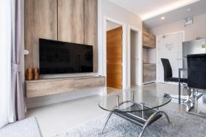 a living room with a tv and a glass table at Condo Vireo Pool View Rawai in Phuket