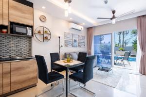 a dining room and living room with a table and chairs at Condo Vireo Pool View Rawai in Phuket