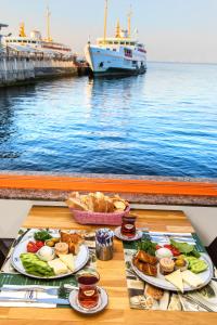 a table with plates of food and a boat in the water at Mom Hotel Buyukada in Adalar