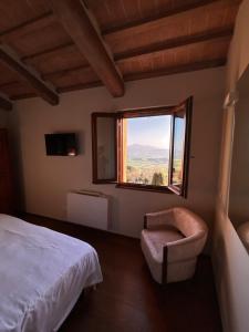 a bedroom with a bed and a chair and a window at CasaGozzante in Pienza