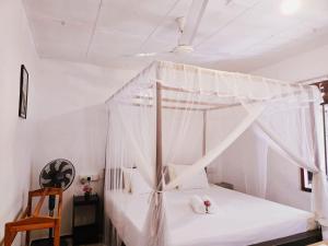 a bedroom with a canopy bed with white curtains at The Coast Haven in Tangalle