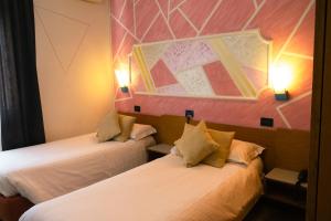 two beds in a room with lights on the wall at Hotel San Marco BB in Boario Terme