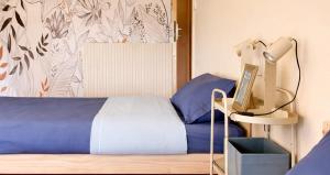 a bedroom with a bed with blue sheets and a lamp at Gîte du Gacet in Trévérien