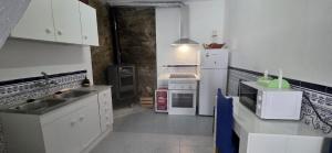 a kitchen with white cabinets and a white refrigerator at Vivienda Turística de Alojamiento Rural - Labrucena in Abrucena