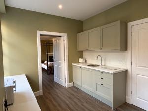 a kitchen with white cabinets and a sink at Bleaton Hallet House Riverside Escape in Kingseat +48 photos