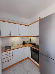 a kitchen with white cabinets and a sink and a refrigerator at Vassilikos Apartment in Flogita