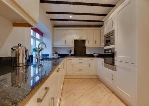 a kitchen with white cabinets and black counter tops at 3 Bed in Caldbergh oc-ds911 in Caldbergh +9 photos