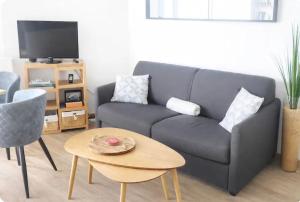 a living room with a blue couch and a table at Superbe appartement face à la mer à Erquy in Erquy