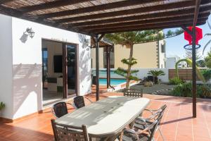 a table and chairs on a patio with a pool at Niteo House in Costa Teguise