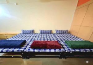 a bed with three pillows on it in a room at Vishram Yatri Niwas in Kolhapur