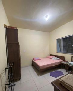 a small bedroom with a pink bed and a window at Casa disponível para temporada in São Roque de Minas